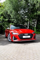 a red sports car parked on a brick road with trees in the background