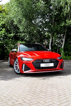 a red sports car parked on a brick road with trees in the background