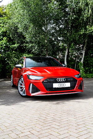 a red sports car parked on a brick road with trees in the background
