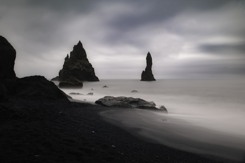 a rocky beach with a large stack of rocks in the water