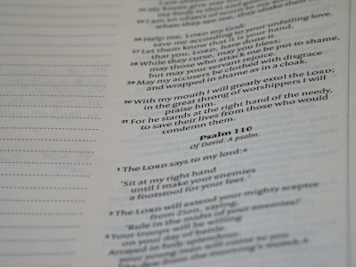 A close-up view of a page from a religious text, containing verses from Psalm 110. The text is printed in a serif font, with some words in bold. The left side of the page features a column of dotted lines for writing notes. The overall appearance is that of a book or Bible page.