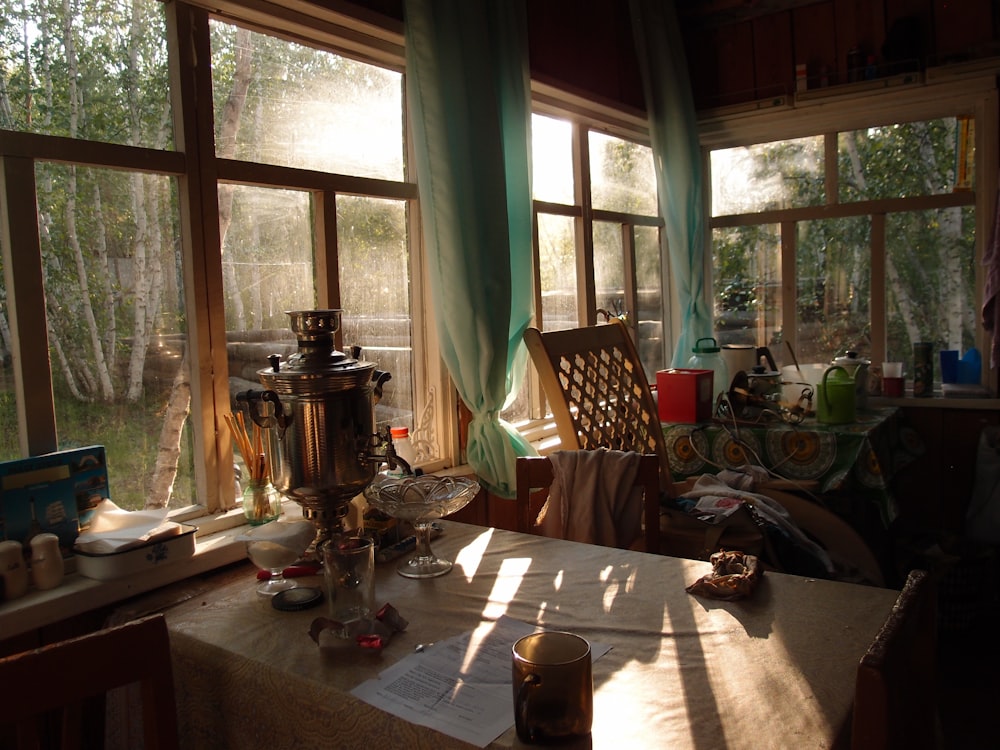 une table avec un pichet et des lunettes devant une fenêtre