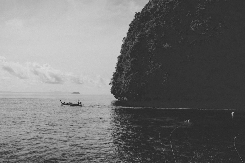 a boat in the water by a cliff