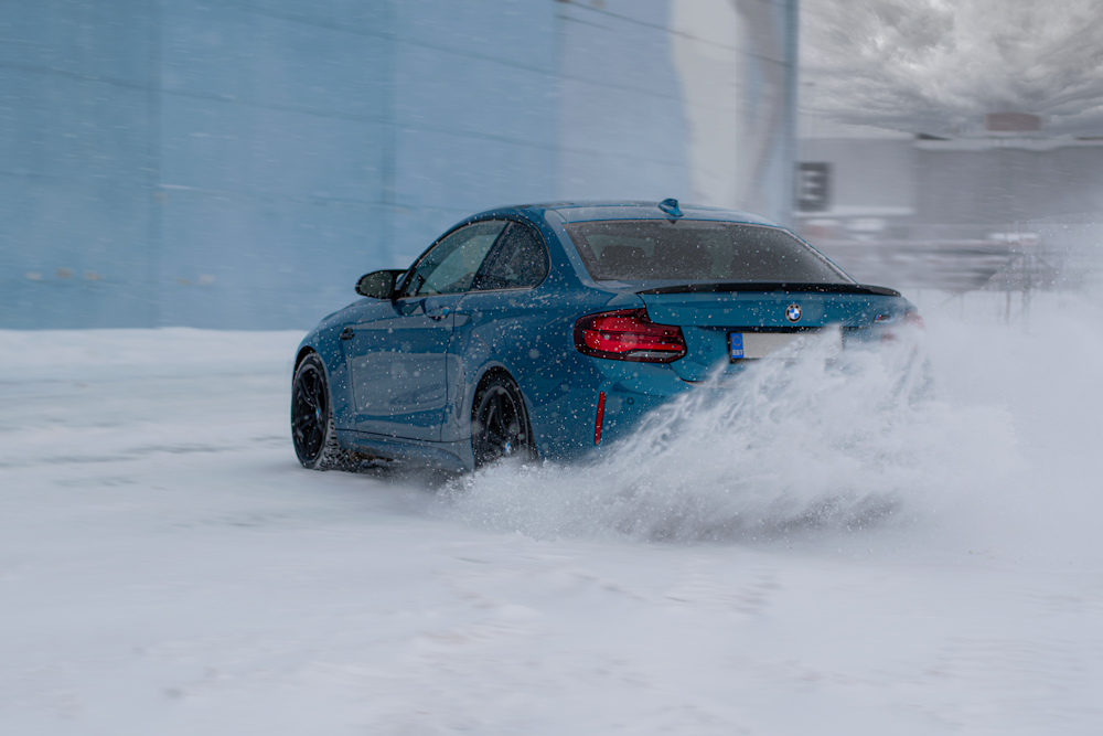 a blue car driving through snow
