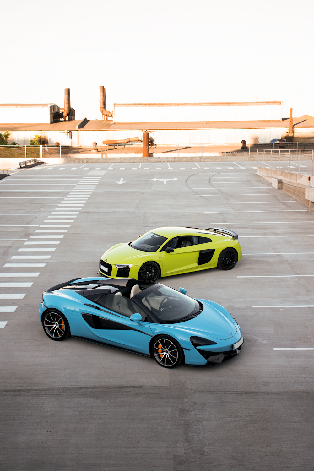 a couple of cars parked on a road with a bridge in the background