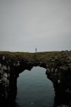 a person standing on a cliff above water