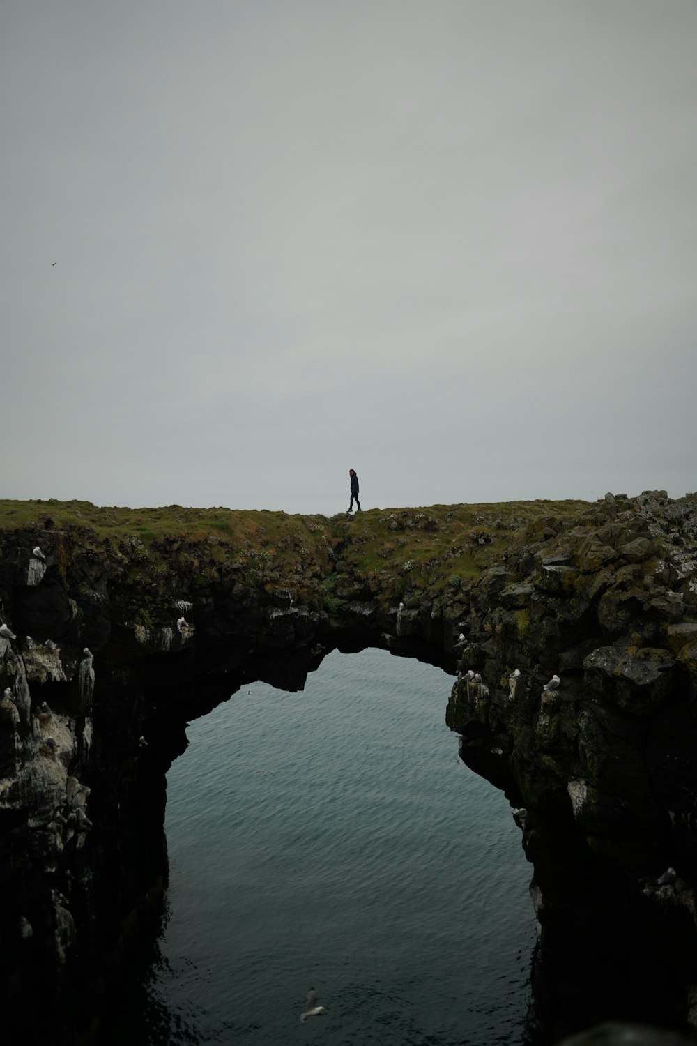 a person standing on a cliff above water
