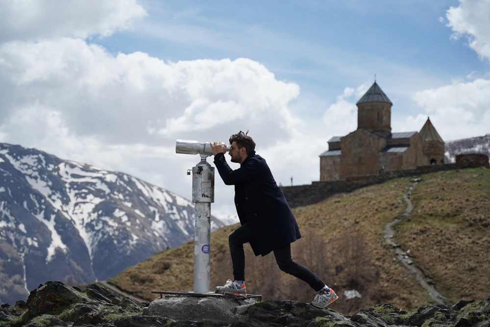 Traveler photographing Gergeti Trinity Church in the Kazbegi mountains