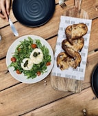 Close-up of a biodegradable bagasse plate holding a fresh salad, set on a rustic wooden table.