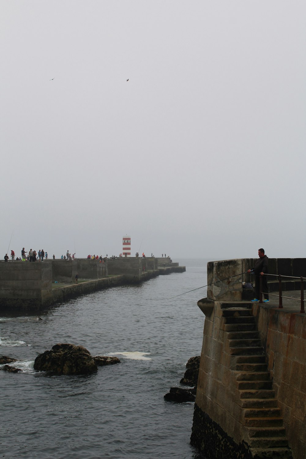 a group of people on a stone wall over water