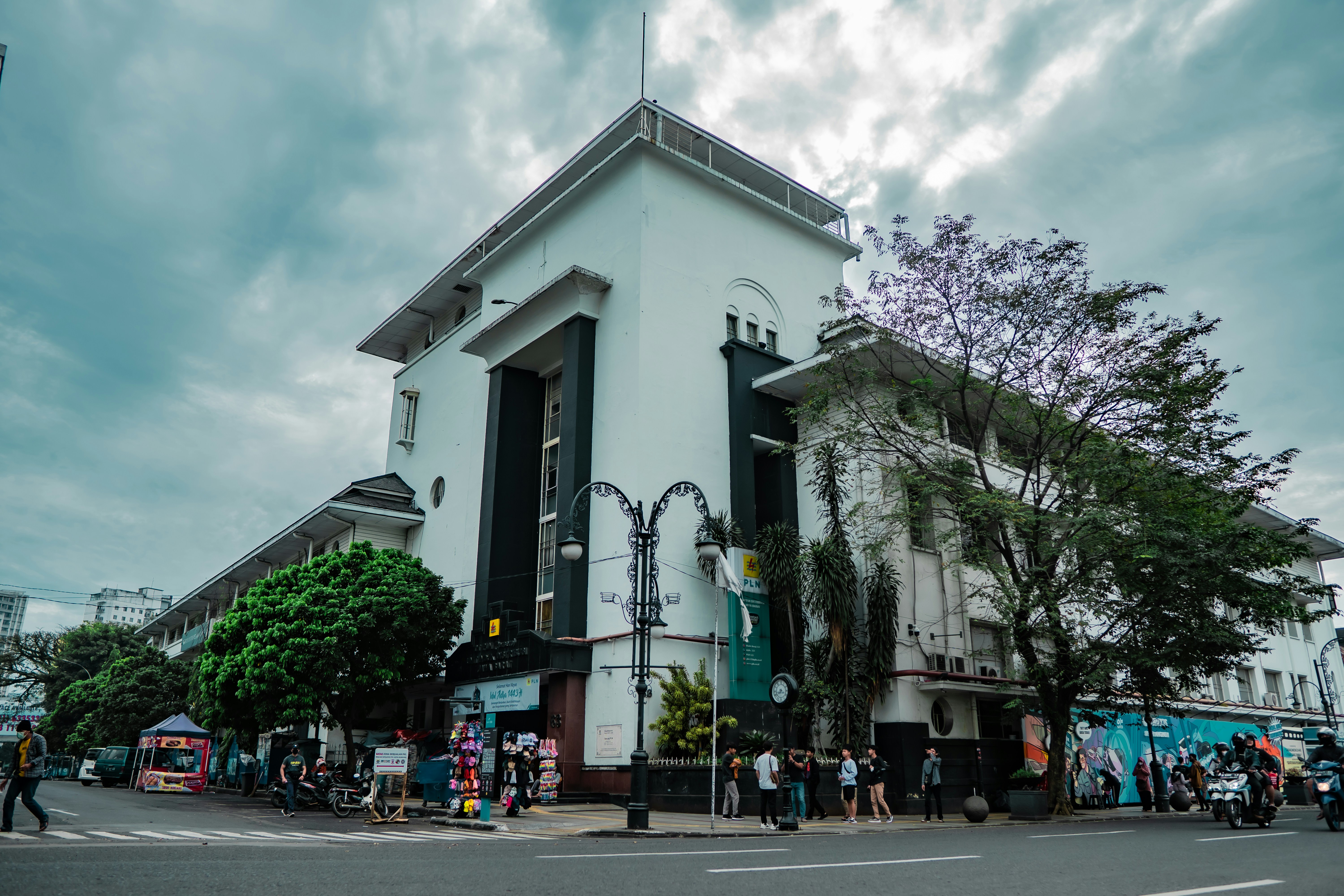 a white building with a street and trees in front of it