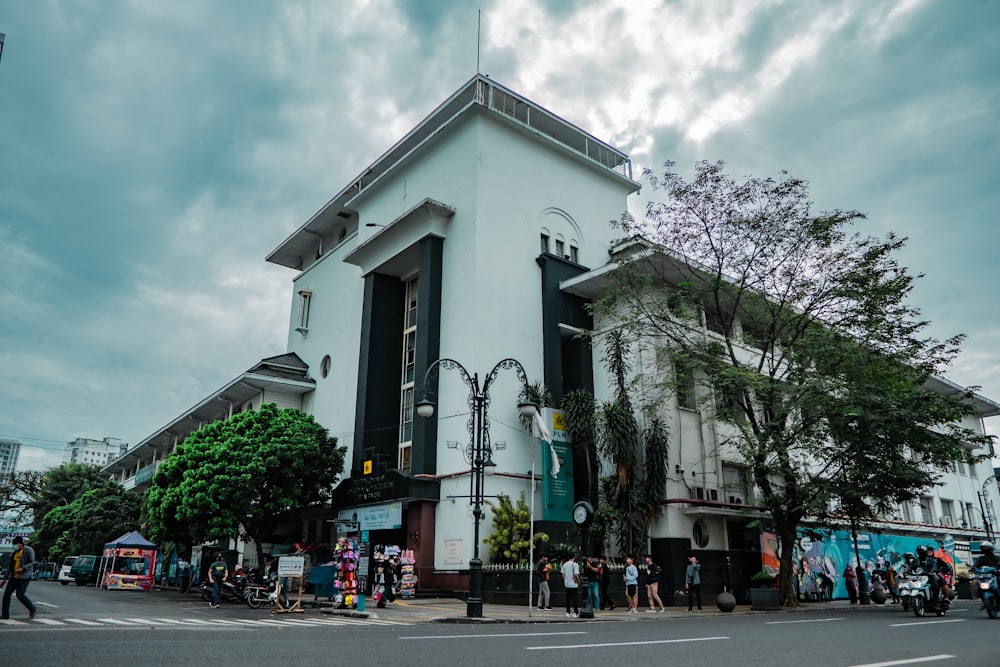 a white building with a street and trees in front of it