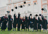 Group of students celebrating graduation day with caps in the air.