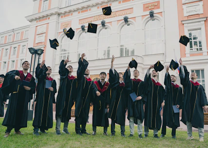 A diverse group of students celebrating with graduation caps at a university campus.