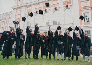 Group of students celebrating graduation day with caps in the air.