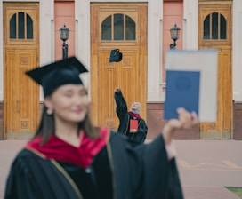 a woman in a graduation cap and gown with a cat on her head