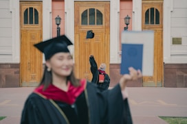 a woman in a graduation cap and gown with a cat on her head