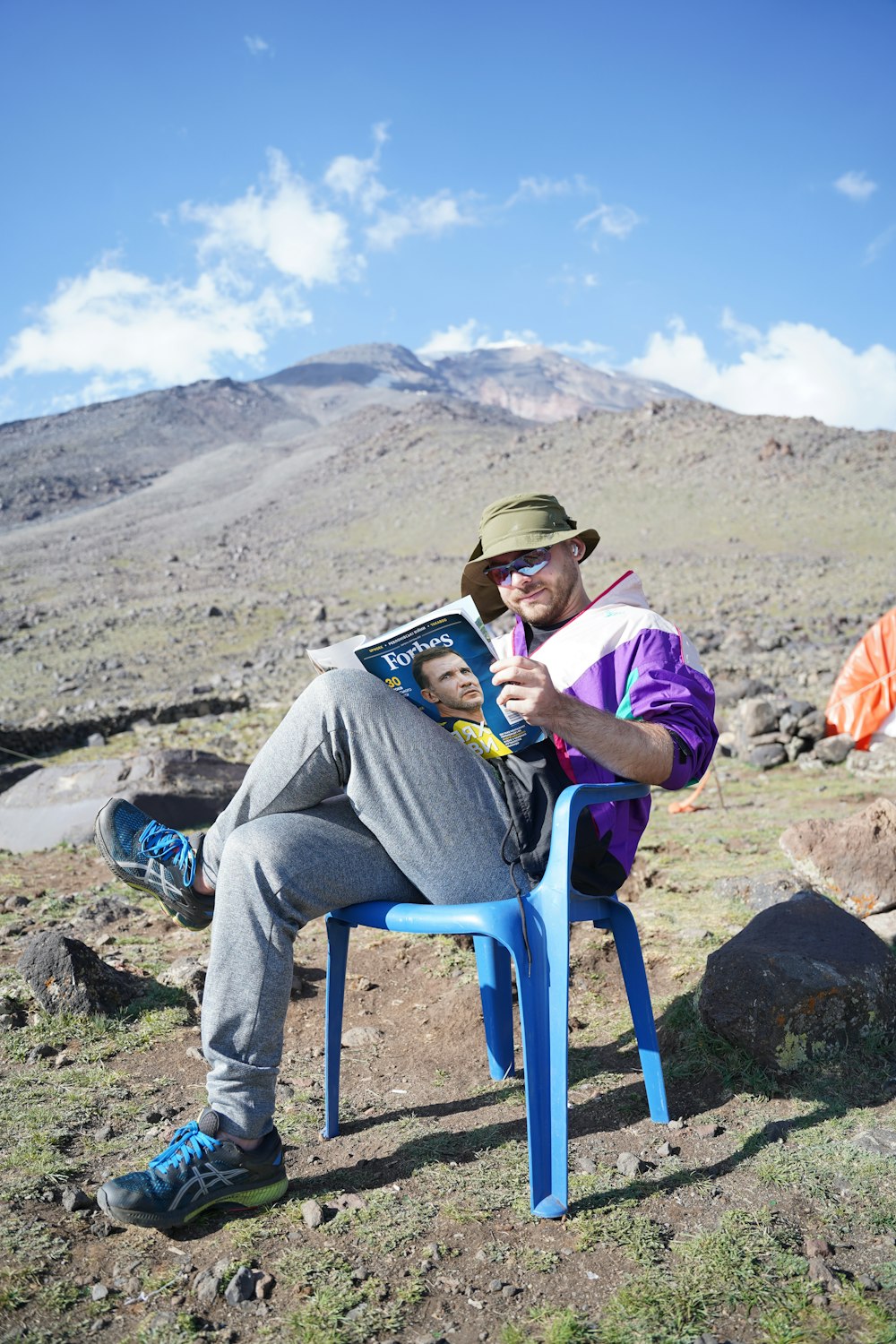 a man and woman sitting on a chair in front of a mountain