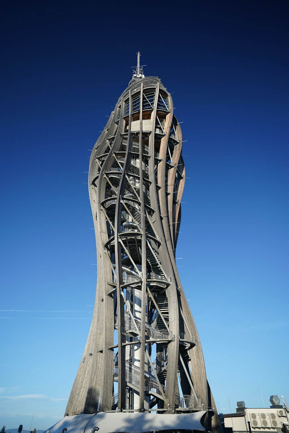 une haute tour métallique avec la tour penchée de Pise en arrière-plan