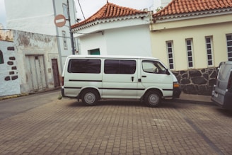 a white van parked on a brick road next to a building