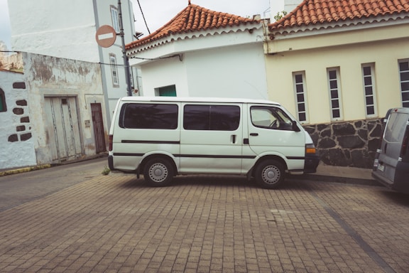 a white van parked on a brick road next to a building