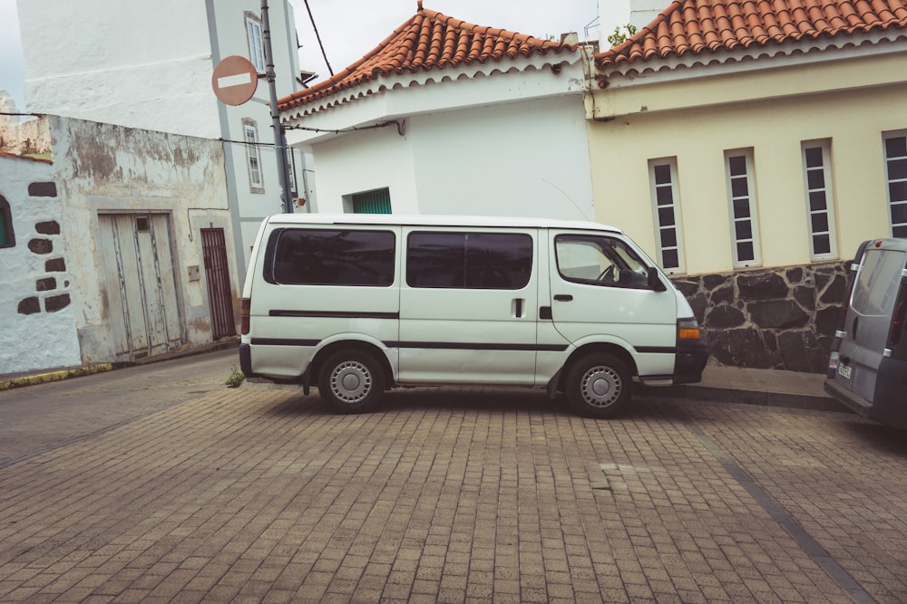 a white van parked on a brick road next to a building