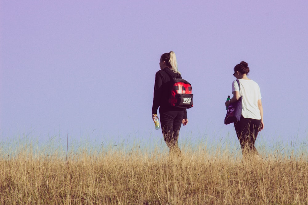 a couple of people walking through tall grass