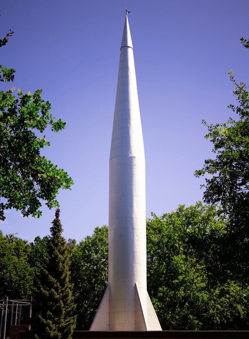 a tall white tower with trees around it