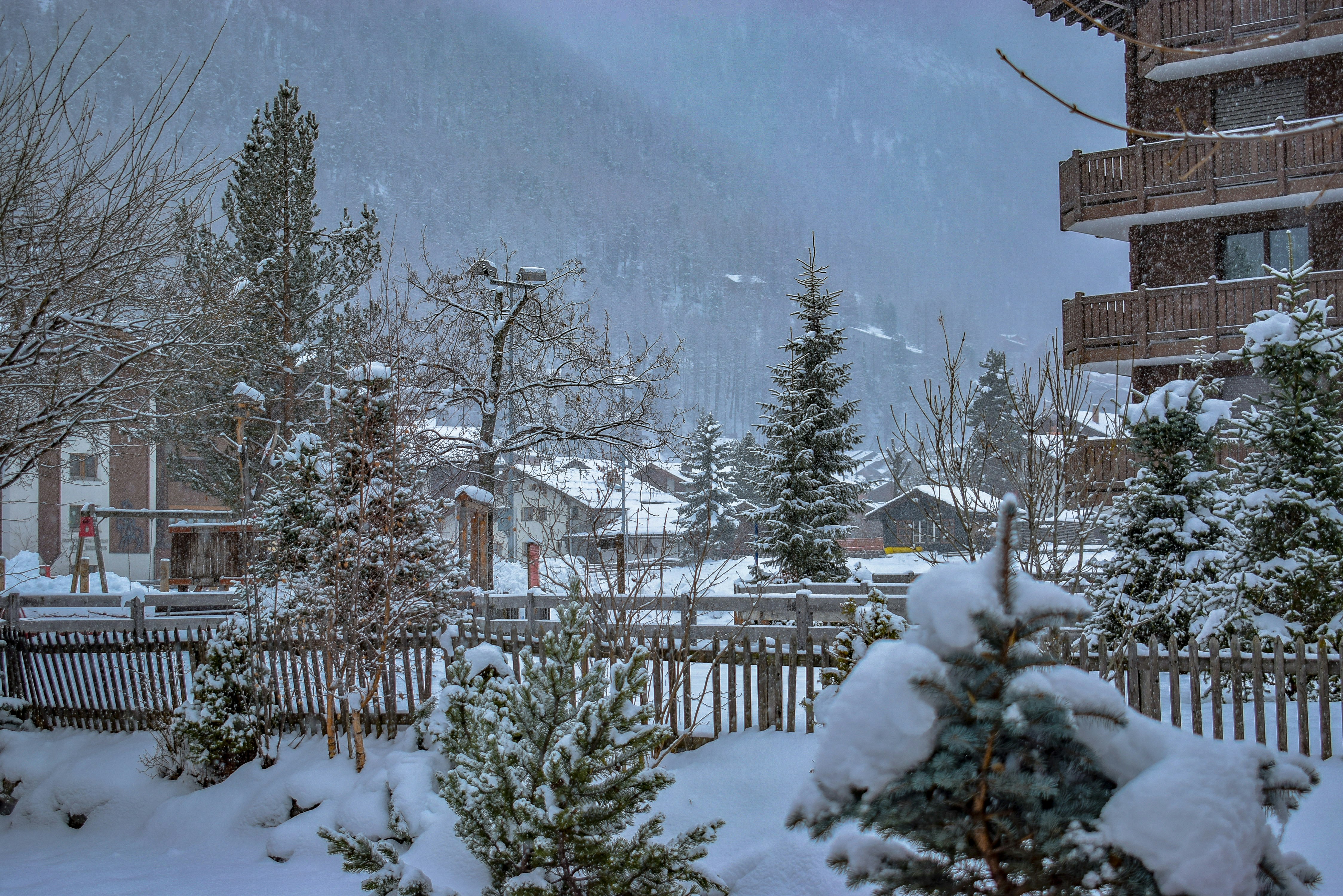 a snowy yard with trees and buildings, snowy day in Zermatt, Swiss Alps, Switzerland