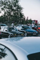 A group of GlocSquad car club members chatting beside their polished cars on an open Saturday.