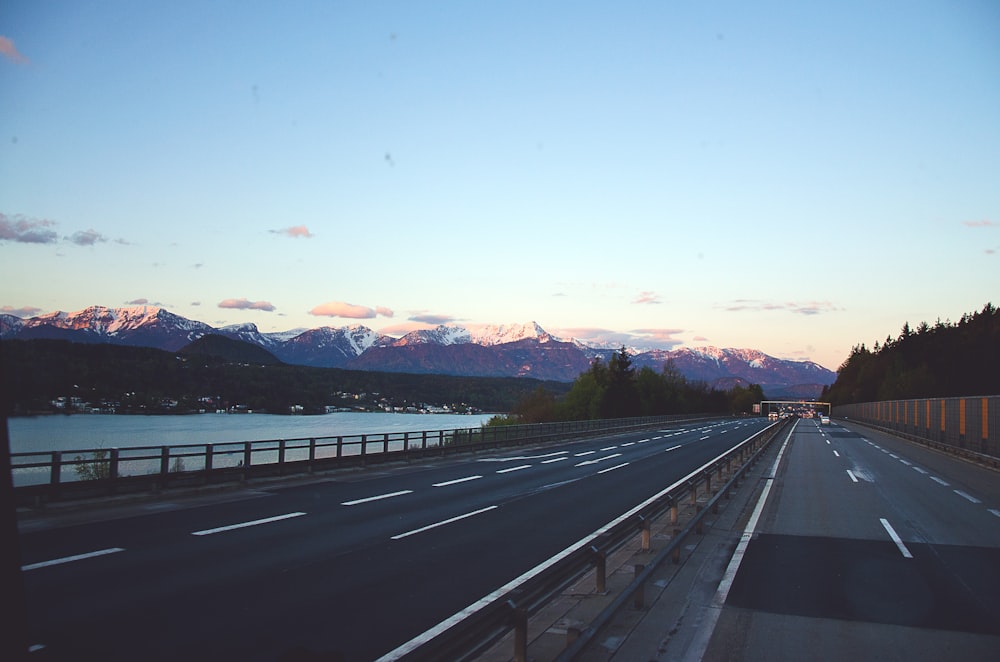 a road with a body of water and mountains in the background