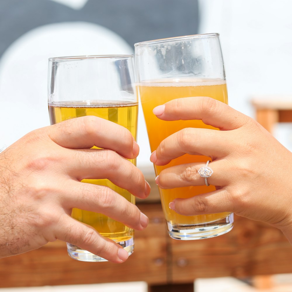 a couple of hands holding glasses of beer