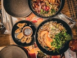 A table set for two with steaming bowls of noodles and chopsticks ready to enjoy.