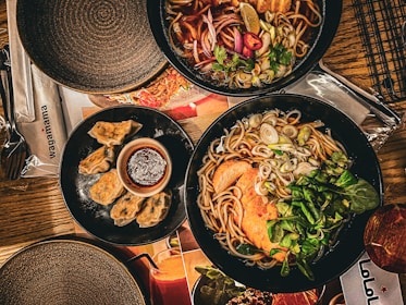 A cozy table setting featuring a steaming bowl of noodles and chopsticks ready to dig in.