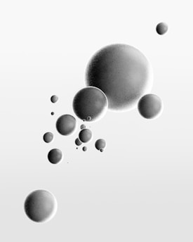 Various sizes of grey spheres appear to be floating against a light gradient background. The spheres are evenly spaced and have a smooth, matte texture.