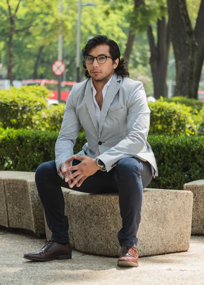 Man in a suit sitting on a stone bench outdoors.