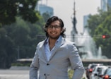 a man in a suit standing in front of a fountain