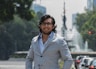 a man in a suit standing in front of a fountain