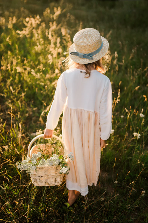 Mulher de roupa clara e chapéu caminhando num campo