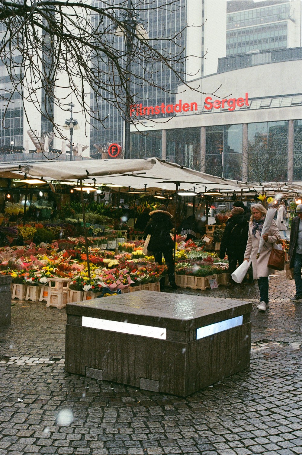 a group of people standing outside a flower stand