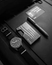 Flat lay of black and white 'Astronaut Alone' accessories arranged symmetrically on a monochrome surface