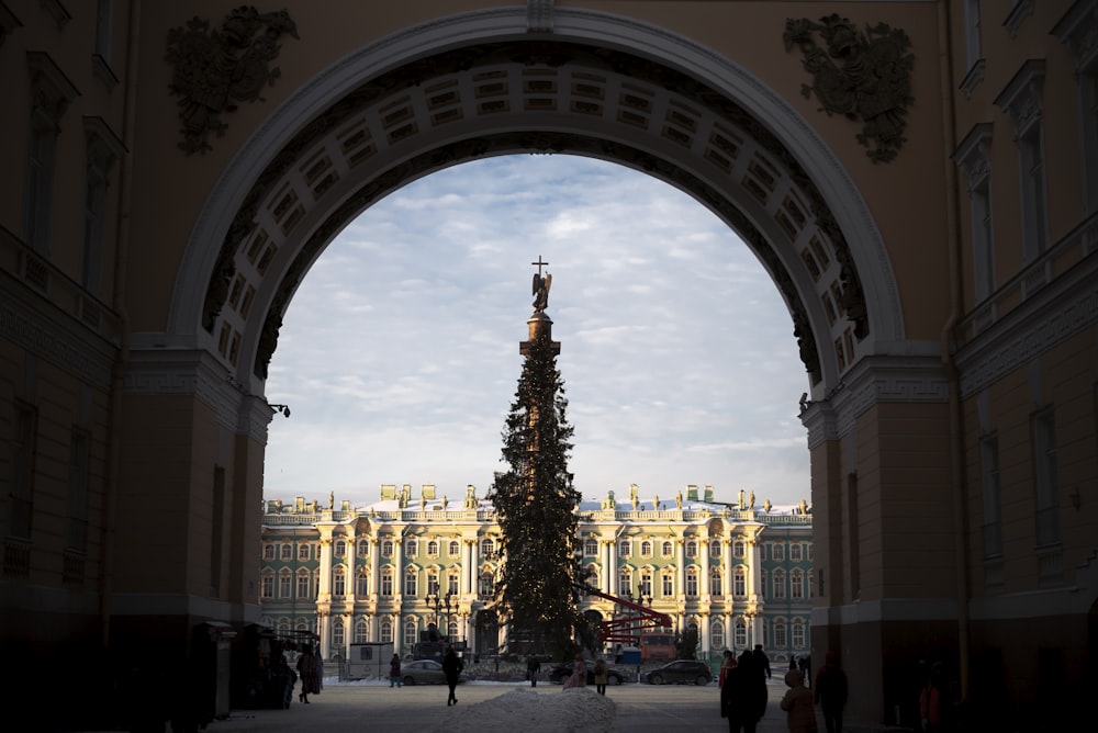 a large arched archway with a tree and a building in the background