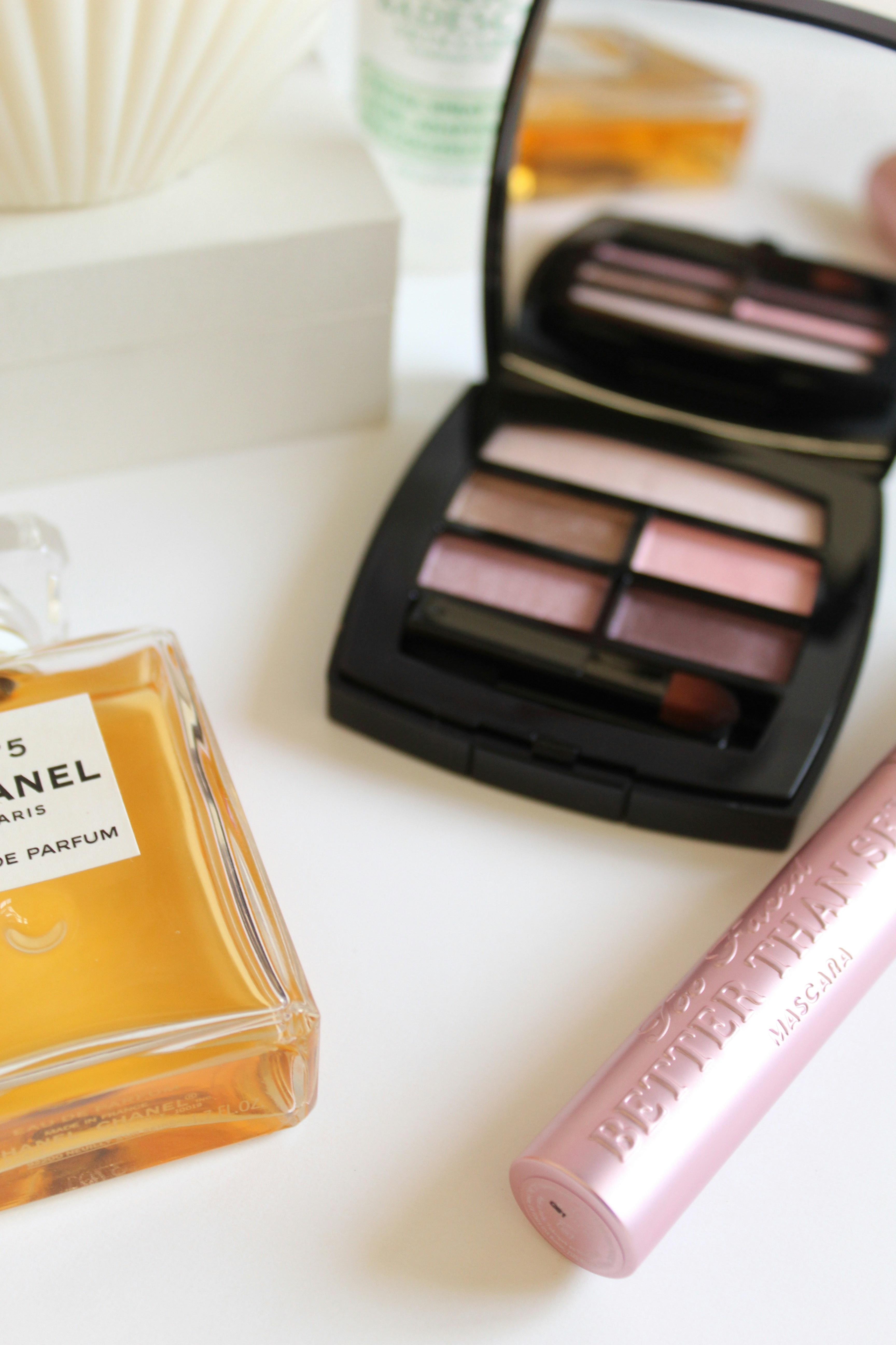 Eye shadow palette and mascara products on pink background