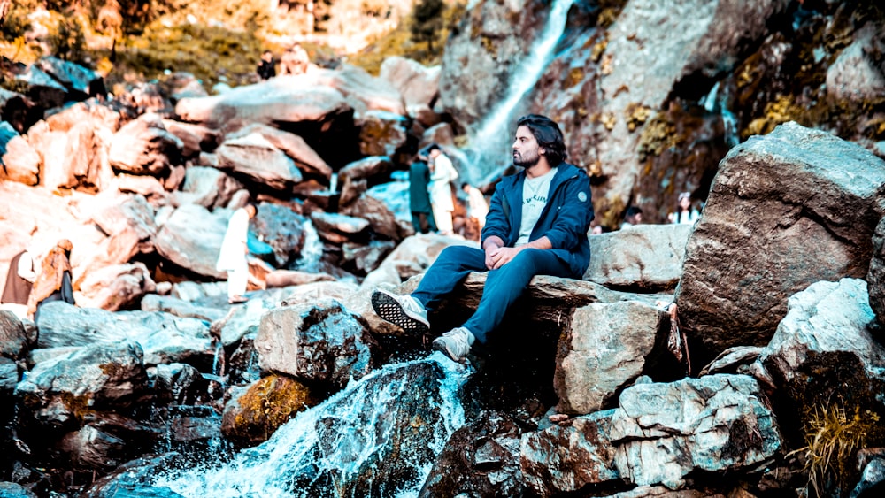 a person sitting on rocks by a waterfall