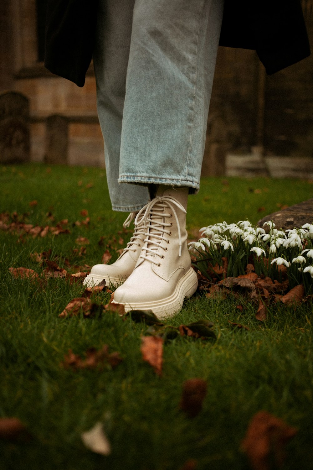 a person's feet in white shoes on grass
