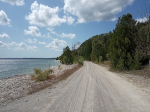 a gravel road next to a body of water