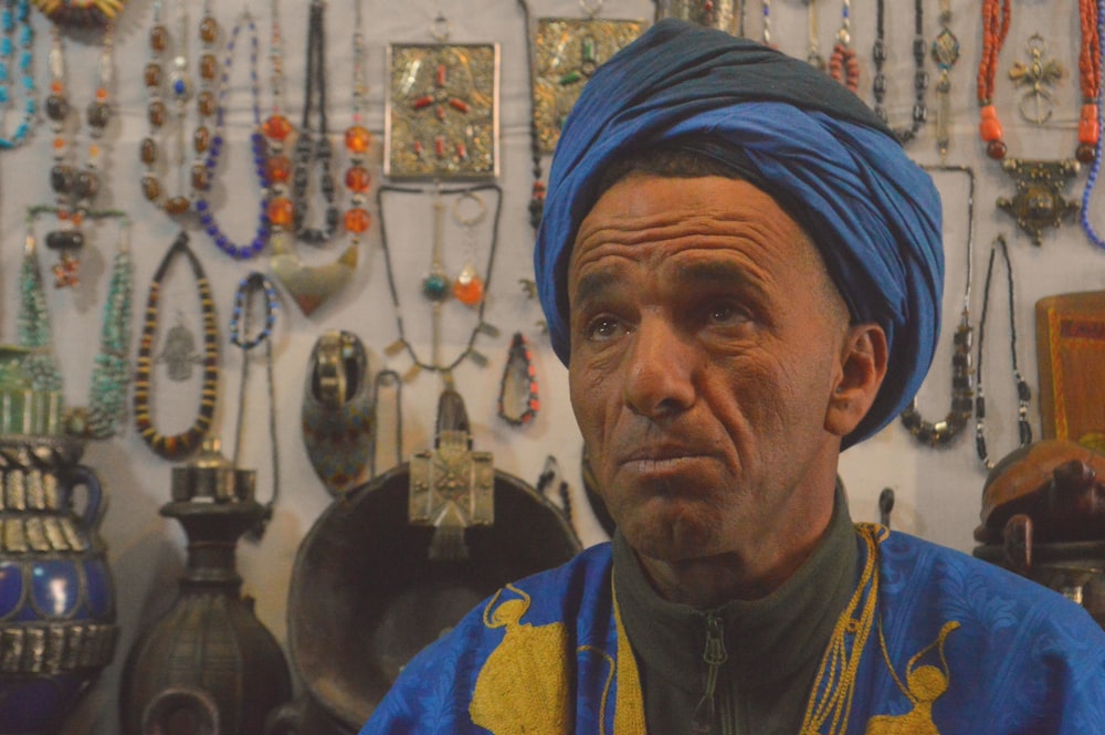 a man with a blue headdress in a room with many antique items