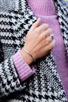 Close-up of a woman’s hand showcasing delicate silver rings paired with a soft cashmere sweater.