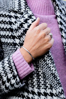 Close-up of a woman’s hand showcasing delicate silver rings paired with a soft cashmere sweater.
