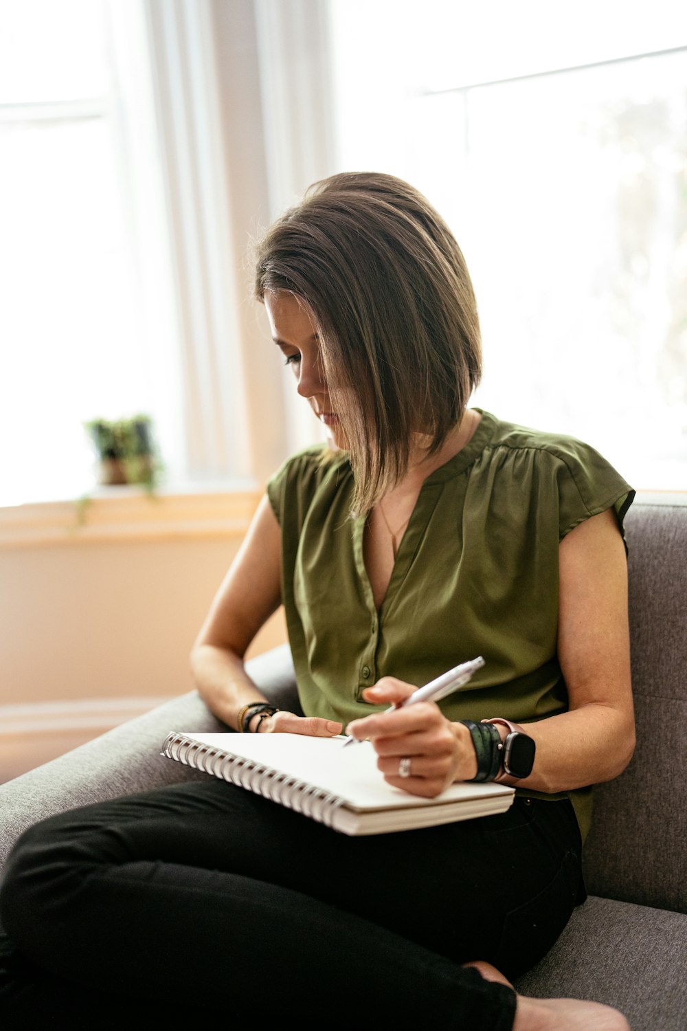 a woman sitting on a couch reading a book